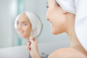 How Red Light Therapy Can Help Regenerate Skin Blog - Looking in Mirror